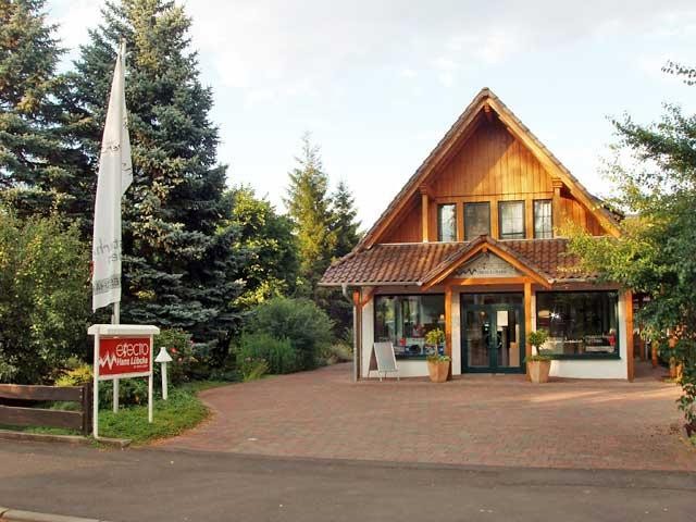 Das Bürogebäude mit Holzgiebel und Glasfront, davor ein gepflasterter Hof.